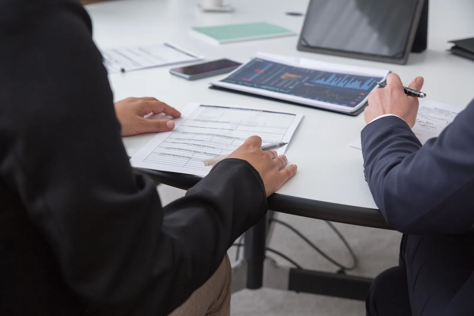 Technical dossier review Two professionals reviewing printed technical documents and data at an office desk