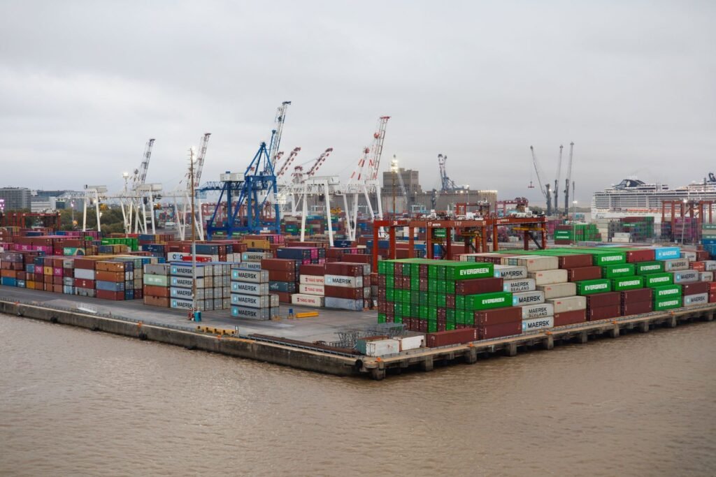 Aerial view of a busy container port with rows of colorful stacked shipping containers and gantry cranes
